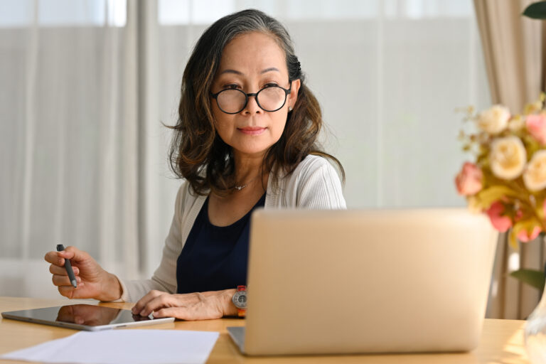 Smiling 60s middle aged business lady remote working from home,