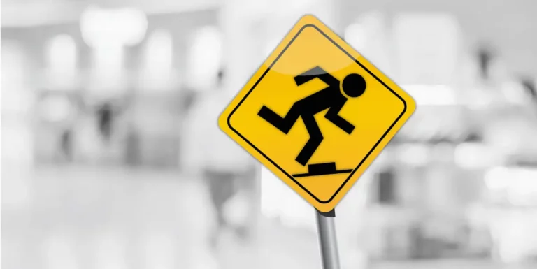 Warnschild mit Symbol für Stolpergefahr auf unscharfem Hintergrund.