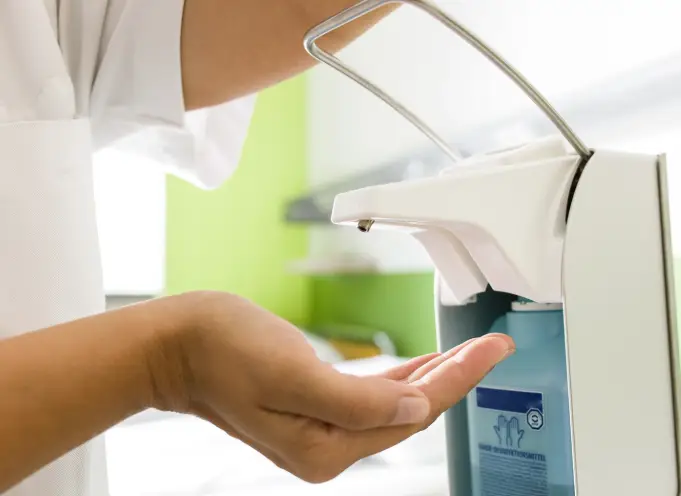 Person entnimmt Händedesinfektionsmittel aus einem Spender.