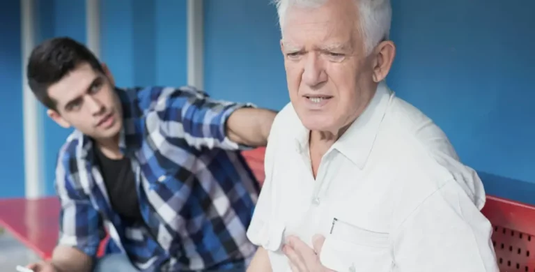 2 Männer, einer fasst sich schmerzverzerrt an die Brust, der andere schaut ihn besorgt an