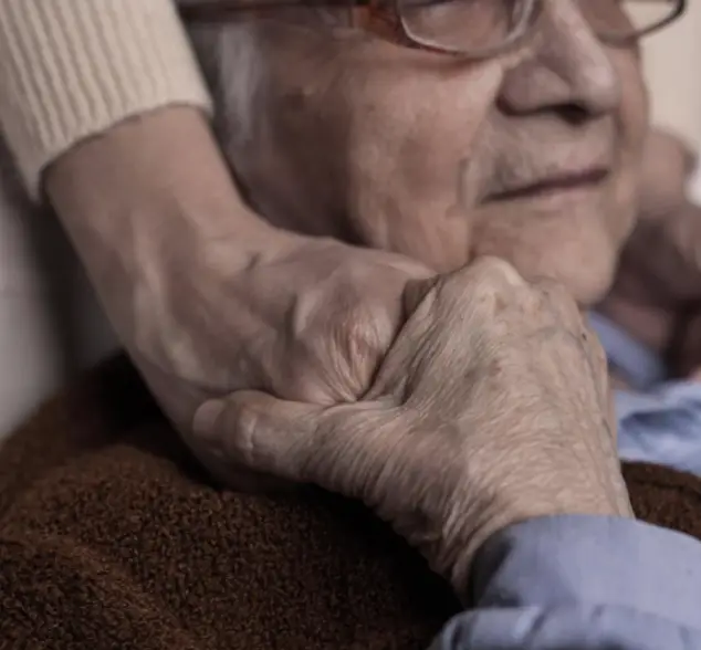 Alte Person wird liebevoll an der Hand gehalten.