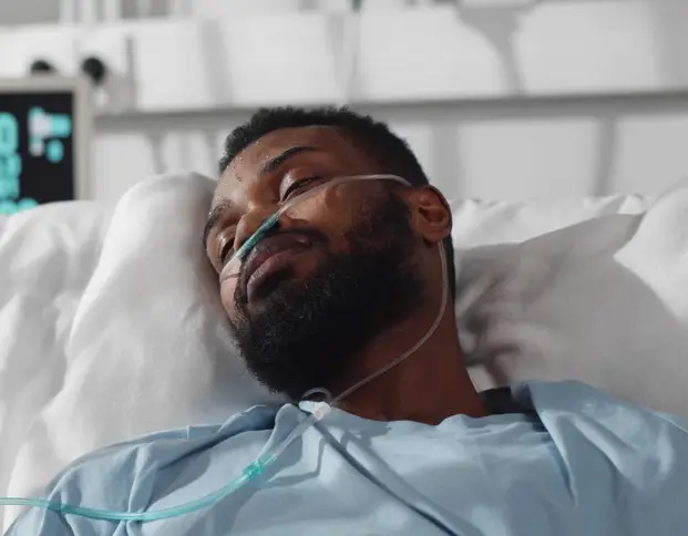 Mann liegt mit Nasensonde im Krankenhausbett.