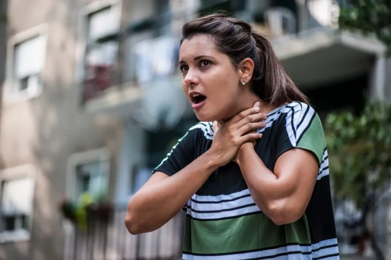 Frau greift sich an den Hals und ringt nach Luft – Anzeichen von Atemnot.