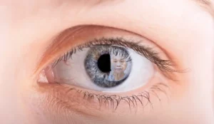 Nahaufnahme eines Auges mit dem Spiegelbild einer älteren Person in der Iris.
