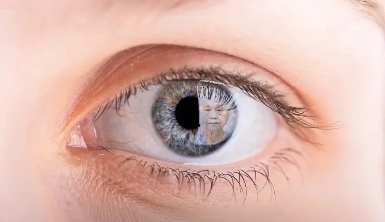 Nahaufnahme eines Auges mit dem Spiegelbild einer älteren Person in der Iris.