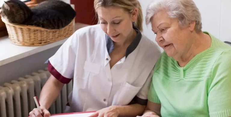 Pflegekraft erklärt älterer Frau ein Dokument, beide schauen gemeinsam darauf.