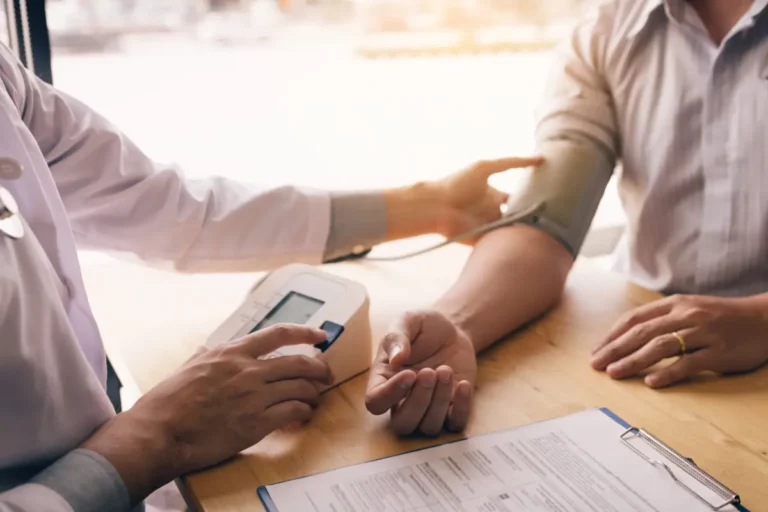 Arzt misst Blutdruck bei einem Patienten.