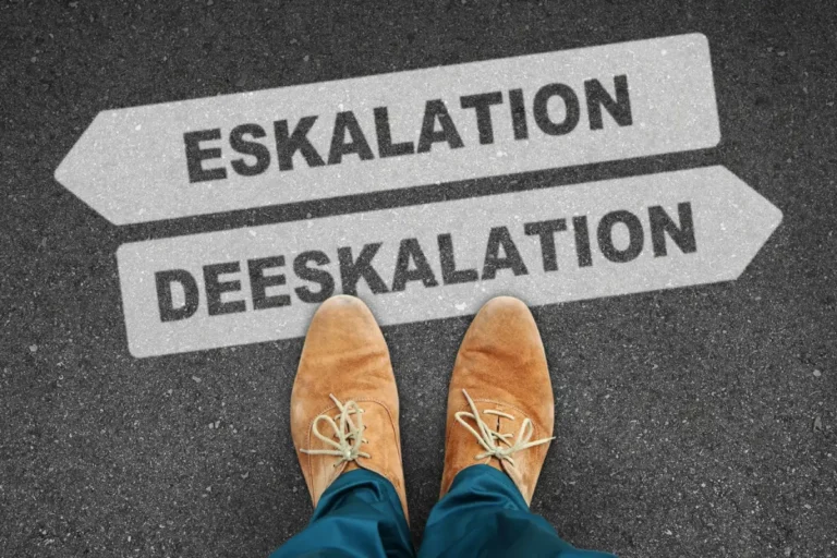 Person steht vor zwei Bodenpfeilen mit der Aufschrift „Eskalation“ und „Deeskalation“.