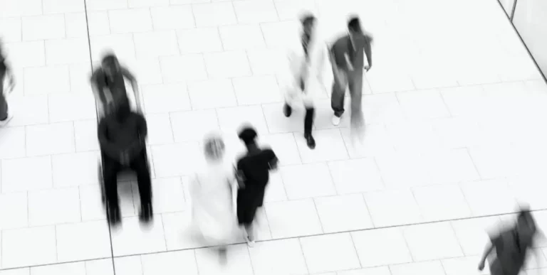 Bewegungsunscharfes Bild von Klinikpersonal und Patient im Rollstuhl von oben.