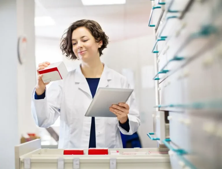 Fachkraft in Apotheke kontrolliert Medikamentenverpackung mit digitalem Gerät.