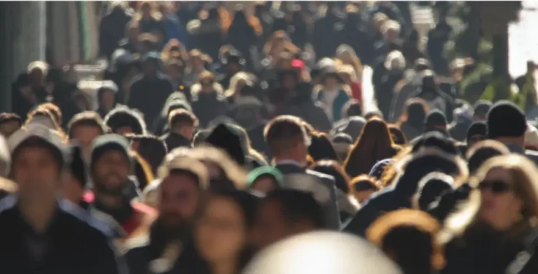 Menschenmenge auf belebter Straße, viele Personen unscharf im Hintergrund.