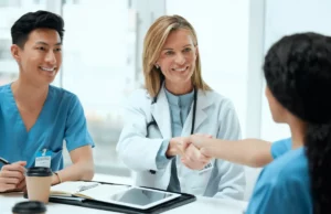 Ärztin gibt neuer Kollegin die Hand bei einem Gespräch.