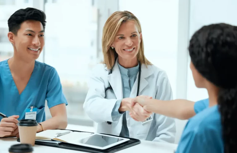 Ärztin gibt neuer Kollegin die Hand bei einem Gespräch.