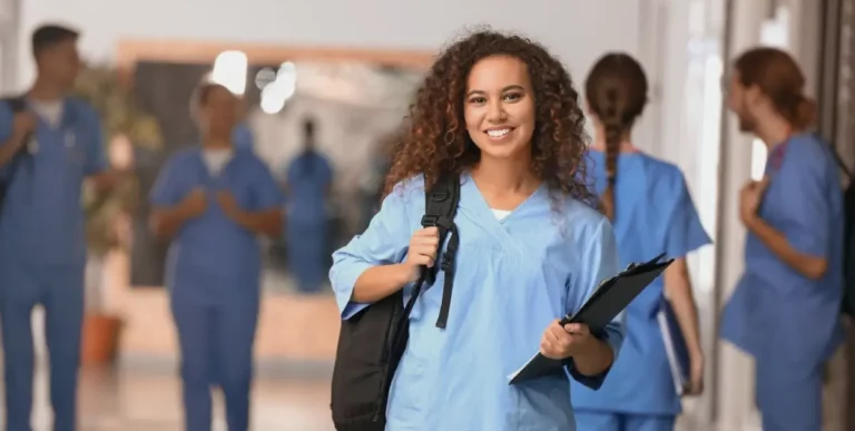 Lächelnde Frau in Pflegekleidung mit einem Ordner in der Hand.