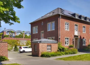 Backsteinhaus mit Solarpanels, Vorgarten und geparktem Auto.