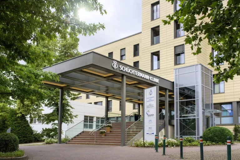 Haupteingang der Schüchtermann-Klinik mit Glasdach und Wegweiser.