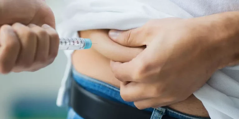 Person spritzt sich Insulin mit einer Einwegspritze in die Bauchfalte.