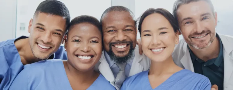 Fünf Pflegepersonen und ärztliches Personal mit guter Stimmung im Gruppenfoto.