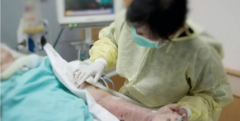 Behandlung einer Hautwunde durch Pflegekraft mit Schutzkleidung.