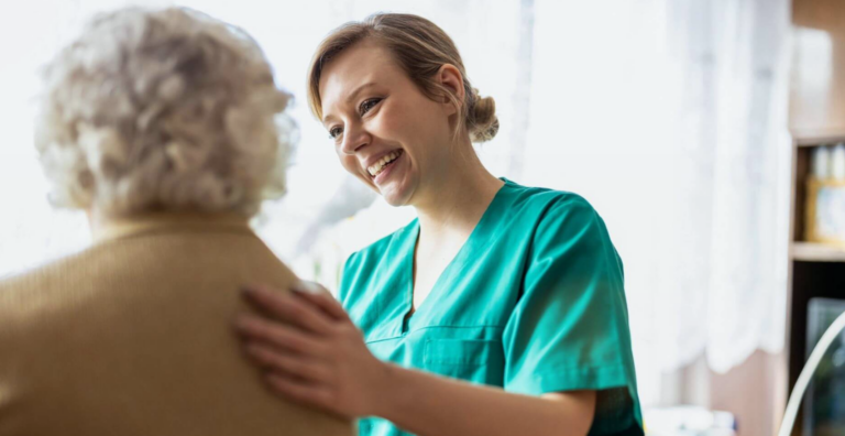 Eine lächelnde Krankenschwester steht neben einer älteren Frau und vermittelt Wärme und Fürsorge.