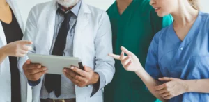 Team aus ärztlichem Personal und Pflegeperson analysiert Daten auf einem Tablet.