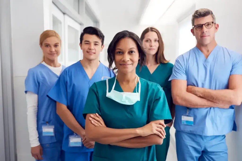 Pflegeteam steht selbstbewusst im Flur eines Krankenhauses