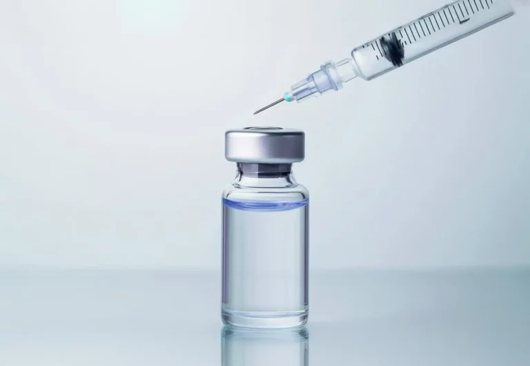 Medikamentenfläschchen mit Flüssigkeit, darüber eine Spritze mit Nadel.
